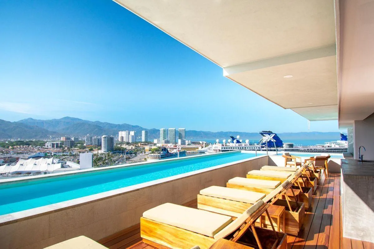 Alberca del rooftop con camastros y vista al mar